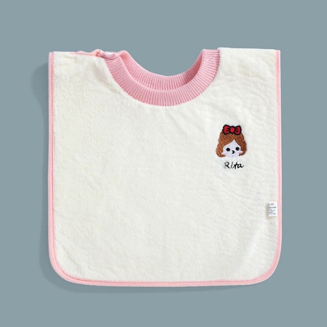 artículos de aseo para niños, ropa que no moja, toallitas húmedas para bebés varones y lactantes — Babero cuadrado frontal color crema con ribete y cuello acanalado rosa; bordado de carita con moño rojo y texto "Rita" en el pecho, etiqueta lateral visible; fondo gris neutro, pensado para alimentación y limpieza diaria y a menudo usado como paño de apoyo durante cambios.