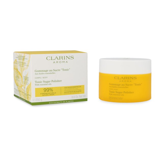 exfoliante corporal tonic sugar polisher clarins Tarro cilíndrico amarillo de 250 g con tapa blanca junto a su caja blanca y verde con ilustración botánica; vista frontal centrada que muestra la marca Clarins y el texto 'Tonic Sugar Polisher'. Producto para cuidado corporal indicado para exfoliación y revitalizar los sentidos según la ficha; también suele utilizarse para una preparación suave de la piel antes de aplicar lociones.