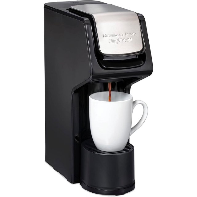 hamilton beach 49918 flexbrew - cafetera de una sola porción compatible con paquetes de cápsulas y molidos, 14 onzas. Vista frontal 3/4 de la cafetera negra con tapa de acero inoxidable sirviendo café en una taza blanca; cuerpo delgado (<5 in) con bandeja de goteo y depósito de agua visible, controles táctiles y soporte para K-Cup o cesta de posos; a menudo usada también para calentar agua para bebidas instantáneas en cocinas pequeñas.