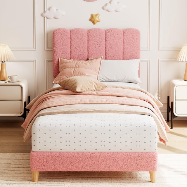 yeshouse cama individual con plataforma tapizada en bouclé y cabecero ondulado para niñas/niños color rosa; vista frontal centrada de cama twin con cabecero de cuatro paneles ondulados tapizados en bouclé, base acolchada baja sobre patas de madera claras, colchón apoyado en listones de madera sin necesidad de somier, ropa de cama y almohadas en tonos rosa, fondo de habitación infantil con mesitas y lámparas. Ideal para dormitorios infantiles o cuartos de invitados.