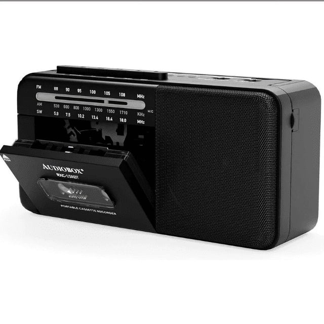 audiobox radio grabadora bluetooth negro vista 3/4 frontal con cassette abierto y parlante derecho; radiograbadora negra con dial AM/FM/SW visible, rejilla de altavoz texturizada y controles superiores; especificaciones indican reproducción por cassette, AM/FM/SW, Bluetooth y USB y batería recargable de 2400 mAh; a menudo usado para llevar música en viajes o picnics.