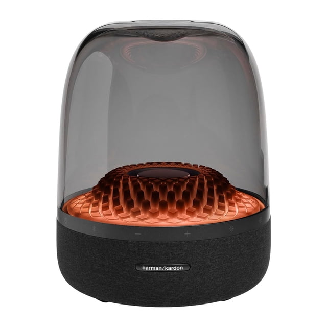 harman kardon aura studio 4 black altavoz doméstico con base textil negra y cúpula transparente, vista frontal centrada que muestra la matriz de 6 altavoces y el subwoofer de 5.2" bajo un anillo interior con iluminación cobre, controles táctiles en el borde y placa de marca Harman Kardon; suele usarse para reproducir audio por empareje inalámbrico con dispositivos móviles.