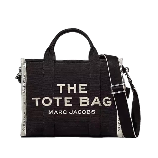 the jacquard tote bag marc jacobs mediana negro, vista frontal centrada de bolso tote mediano en tejido jacquard con logotipo frontal "THE TOTE BAG MARC JACOBS", asas superiores y correa cruzada de cincha ajustable y extraíble colocada a la derecha, cierre de cremallera superior y bandas laterales contrastantes con texto; incluye 2 bolsillos interiores con cremallera y 2 bolsillos abiertos según ficha, a menudo usado también para llevar documentos A4 o una tablet pequeña.