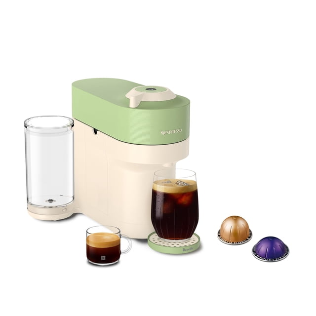 cafetera nespresso vertuo pop+ summer limited edition Verde by Nespresso, vista 3/4 frontal de máquina compacta crema con tapa pistacho y depósito de agua transparente; posavasos con vaso alto de café con hielo, taza de expreso y dos cápsulas que ilustran formatos de servicio.