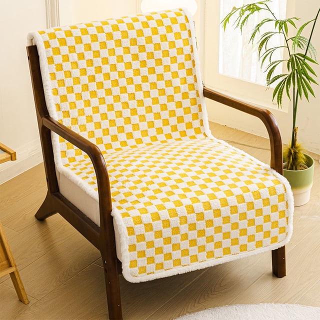 sillón reclinable de oficina con cojín de asiento y respaldo integrados, alfombrilla gruesa antideslizante color amarillo, funda acolchada de cuadros amarillos y blancos vista 3/4 frontal sobre sillón de madera, borde con ribete blanco y textura acolchada visible, colocada en sala junto a maceta y ventana; apta para sillas, taburetes, sofás y sillones reclinables, y a menudo usada también como protector de muebles en zonas de alto uso.