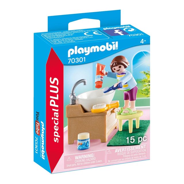 niña con lavabo playmobil special plus 15 piezas Figura de niña Playmobil junto a lavabo blanco sobre mueble beige con grifo plateado; incluye taburete verde, cepillo, pasta dental y frasco pequeño como accesorios, empaque Special Plus visible.