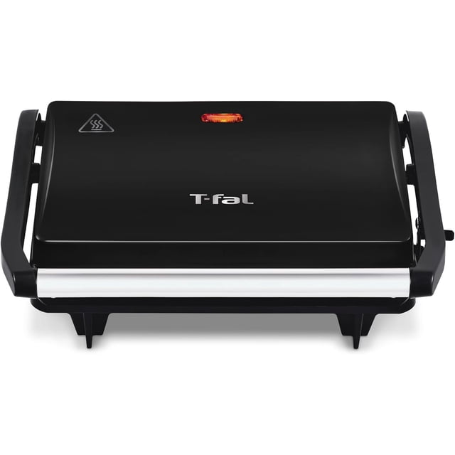 t-fal | parrilla grill sandwichera negra con antiadherente | panninis, tortas, sandwiches | sw3318mx Parrilla grill sandwichera negra T-fal, vista frontal cerrada con logo T-fal en la tapa, carcasa negra, asa frontal cromada, luz LED roja indicadora superior y símbolo de calor; compacta con bisagras laterales y patas cortas; placas antiadherentes fáciles de limpiar, ideal para dorar paninis, tortas, carnes y verduras en la cocina.
