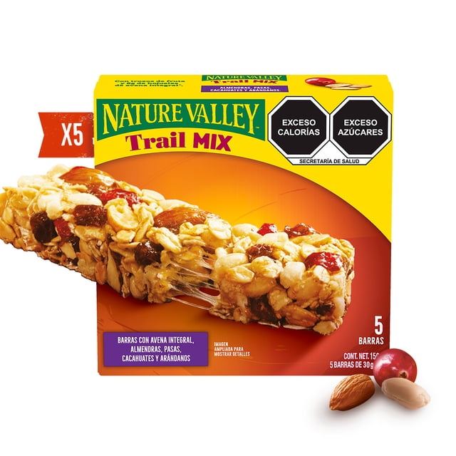 barras de granola nature valley trail mix 5 pzs Caja frontal con 5 barras; vista 3/4 de una barra mostrando avena integral y trozos visibles de almendra, cacahuate, pasas y arándanos sobre fondo amarillo-naranja, sellos de 'Exceso calorías' y 'Exceso azúcares' y etiqueta que indica 5 barras; adecuada como snack para llevar.