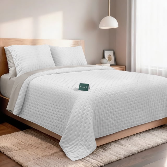 set de 7 piezas edredón ligero y sábanas queen dreamlab, colcha para cualquier temporada, hipoalergénica, diseño trébol blanco, beige — cama queen vista frontal con colcha ligera blanca acolchada en patrón trébol y borde beige; incluye dos fundas decorativas y juego de sábanas ajustables visibles; tela de microfibra doble cepillado de aspecto mate y textura acolchada, situado en dormitorio minimalista con cabecero de madera clara. También suele utilizarse como colcha ligera de verano ideal para climas cálidos.