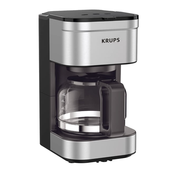 krups simply brew 5 cup coffee maker, cold brew, drip free & keep warm functions, stainless steel coffee maker silver and black — Cafetera de filtro de 5 tazas en vista frontal 3/4 con cuerpo de acero inoxidable plateado y paneles negros, jarra de vidrio con mango y marcas de nivel, tapa superior de llenado, boquilla antigoteo y base sólida; compacta para espacios pequeños y a menudo usada también para enfriar porciones pequeñas en recipientes independientes.