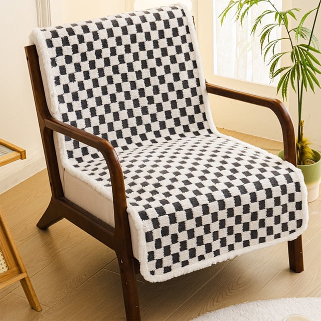 sillón reclinable de oficina con cojín de asiento y respaldo integrados, alfombrilla gruesa antideslizante apto para sillas taburetes sofás y sillones reclinables — vista 3/4 frontal de funda acolchada sobre un sillón de madera; patrón cuadriculado blanco y negro en tejido texturizado, ribete blanco mullido alrededor, acolchado en asiento y respaldo y superficie con textura antideslizante, ambientado en interior con piso laminado y planta junto a la ventana; también suele usarse para proteger y homologar comodidad en sillas de oficina o descanso.