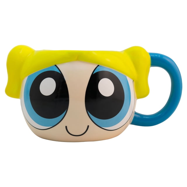 taza grande de cerámica, diseño esculpido en 3d, chicas super poderosas, modelo burbuja, capacidad 591 mililitros — Vista frontal centrada de la taza multicolor con la cara de Burbuja: ojos impresos grandes en azul y negro, sonrisa minimalista, cabello esculpido amarillo brillante y asa circular azul a la derecha; 11 cm de alto, 8 cm de diámetro (5 cm con asa), acabado cerámico brillante, diseñada para uso diario y colección y a menudo usada como pieza decorativa en repisas.