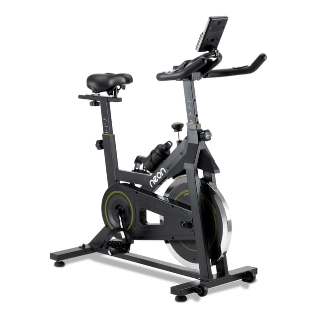 bicicleta fija neon pro para spinning 18 kg bifipro-18 negro, vista 3/4 frontal con estructura de acero y asiento PU ajustable; rueda de inercia 18 kg, transmisión por correa y freno de fricción; manubrio con soporte para celular, pantalla LCD que muestra tiempo, distancia, calorías y velocidad, incluye portabotellas; adecuada para entrenar en espacios compactos.