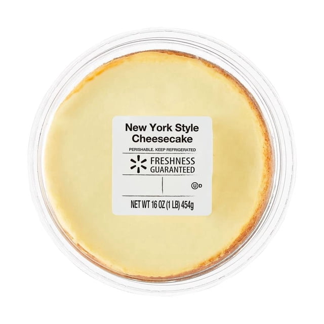 tarta de queso freshness guaranteed estilo new york 8 rebanadas vista cenital de cheesecake entero en envase plástico transparente con borde dorado; etiqueta central blanca muestra "New York Style Cheesecake", marca Freshness Guaranteed y peso 454 g; conservar refrigerado. Postre listo para rebanar, a menudo usado para servir porciones en reuniones.