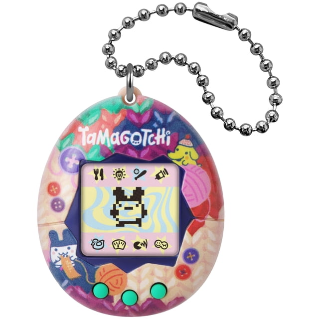 juego electrónico tamagotchi original tama sewing multicolor — Vista frontal del Tamagotchi tipo huevo con cadena metálica; carcasa multicolor con motivos de costura y logo Tamagotchi arriba, pantalla LCD que muestra mascota pixelada en blanco y negro y tres botones redondos verdes debajo; anilla superior para colgar. A menudo usado como artículo de colección o juguete portátil para mayores de 8 años.