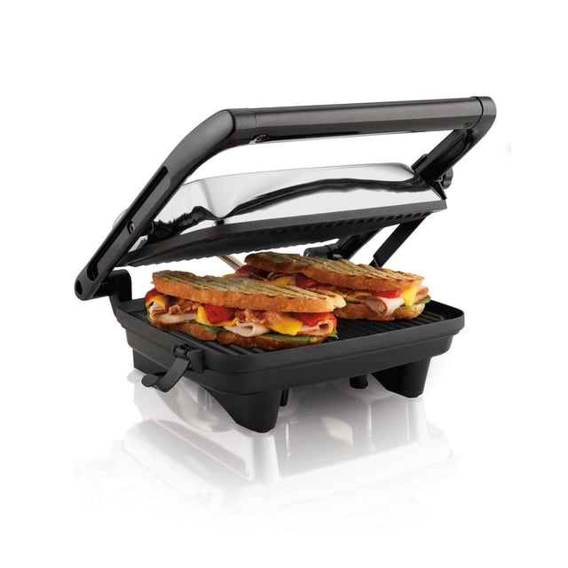 prensa para emparedados hamilton beach tipo panini Parrilla Hamilton Beach negra con rejillas antiadherentes 10" x 8" y almacenamiento vertical; vista 3/4 frontal con la tapa flotante abierta mostrando 2–3 sándwiches grillados, base negra con ranuras de cocción, luz indicadora y diseño compacto para fácil guardado.
