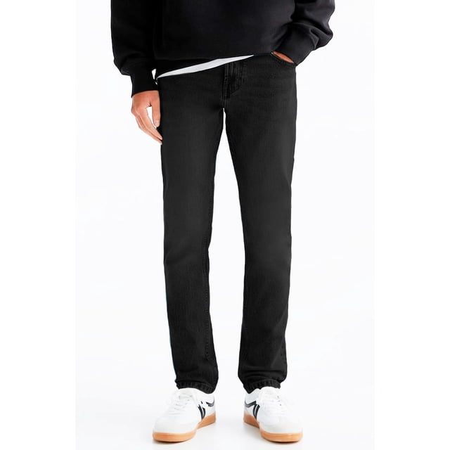 pantalón recto para hombre shendy vendy mezclilla strech clasico con bolsillo en Negro, vista frontal a medio cuerpo mostrando corte recto y tiro medio, textura denim oscura y costuras visibles en piernas y pretina; ajuste relajado hasta el tobillo combinado con sudadera negra y tenis blancos. Ideal para uso casual y frecuentemente usado como prenda de viaje por su comodidad.
