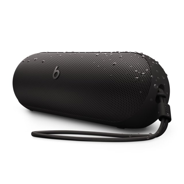 bocina inalambrica beats pill negro mate Bocina Beats Pill en negro mate, vista frontal inclinada 3/4 con rejilla perforada y logotipo 'b' visible; gotas de agua visibles sobre la superficie, cordón de silicona extraíble en el lateral y base ligeramente inclinada para proyectar sonido; clasificación IP67 y hasta 24 horas de batería según especificaciones; también suele usarse para llamadas manos libres y cargar un teléfono con USB‑C.