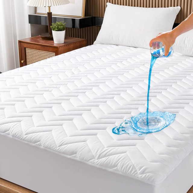 protector de colchón impermeable acolchado unilibra tamaño queen blanco, vista 3/4 frontal del cubrecolchón tipo sábana bajera con patrón acolchado geométrico y superficie transpirable; faldón elástico profundo ajustado para protección 360°, se muestra líquido vertiéndose sobre la tela para ilustrar la membrana impermeable; también suele usarse para proteger colchones de huéspedes o camas infantiles.