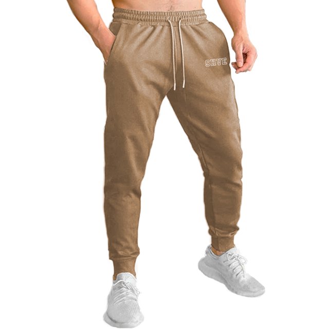 pants jogger para hombre shendy vendy deportivo slim fit elástico, vista frontal centrada de jogger color café claro con cintura elástica acanalada y cordón con puntas plateadas, corte slim fit y puños inferiores ajustados, bolsillos laterales visibles y logotipo en pierna derecha; tela ligera y suave, ideal para ejercicio ligero o uso casual.