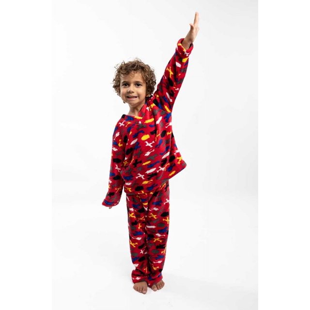 pijama para niños aviones, afelpada, suave y calientita dos piezas; niño en vista 3/4 con sudadera y pantalón de polar mink estampado multicolor de aviones sobre fondo rojo, cuello redondo y puños, corte holgado y textura mullida visible sobre fondo blanco; también suele usarse como conjunto cómodo para jugar en casa.