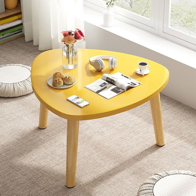 mesa triangular curva de madera para sala de estar Yellow, mesa de centro triangular curva 40x40x30cm; vista 3/4 frontal de sobremesa triangular curvada amarilla con revista, auriculares y taza; patas cónicas de madera sólida de 30 cm con topes antideslizantes, esquinas redondeadas y bordes pulidos; colocada junto a un alféizar de ventana sobre alfombra clara, adecuada como mesa de té para balcón o mesa de piso para dormitorio.
